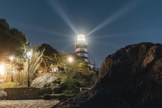The Sile lighthouse at night. Radiant light over rocks and pine trees. Sile, Istanbul, Turkey