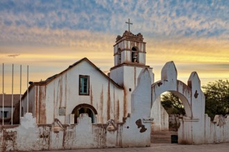 Church at dusk with warm colours and a striking church cross in the foreground, The church of San