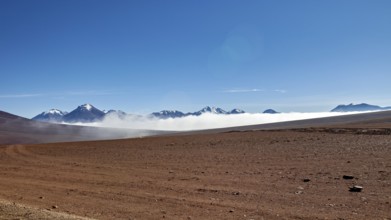 Dry desert plain with distant mountains and wafts of mist under a clear sky, The landscape at San