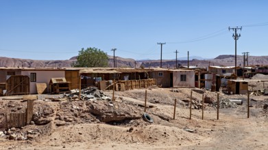 An arid landscape with simple buildings and electricity pylons under a clear sky, The town of San
