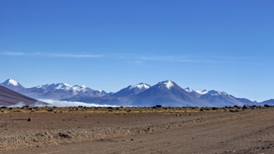 Vast dry desert landscape with snow-capped mountains and clear blue sky, The landscape at San Pedro