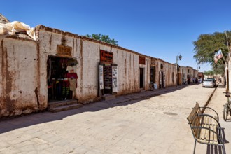 A quiet stretch of street with shops in old buildings along a cobbled path under a blue sky, The