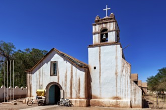 Historic church with bicycle in front of a clear blue sky, cross on the bell tower, The church of