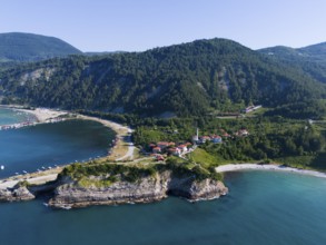 Panoramic view of cliffs and bays with green landscape and calm sea under blue sky, aerial view,