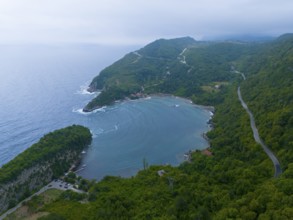 Aerial view of a quiet coastline with wooded mountains and a winding road, aerial view, Gideros