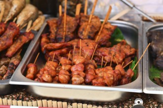 Grilled red marinated Thai meat skewers at street food market