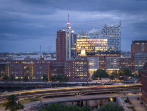 Evening city view with illuminated Elbphilharmonie, underground U3 and Speicherstadt under cloudy