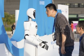 A person looks at a robot at the IFA consumer electronics exhibition on the exhibition grounds,