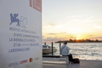 Venice, Italy - 2 September 2025: Passengers sit on the jetty at the Lido at sunset, waiting for