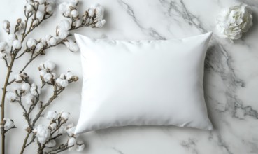 A white pillow framed by cotton branches on a marble background with soft shadows. AI generated