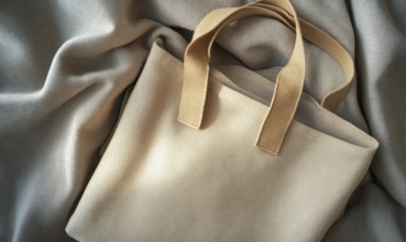 A tan purse with a brown strap sits on a grey cloth. The purse is open and the strap is visible. AI
