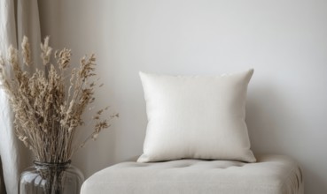 A white pillow sits on a bench next to a vase of dried flowers. The pillow is unmade and the