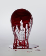 Generic human dummy head made of glass, overwhelmed with red fluid in light grey back