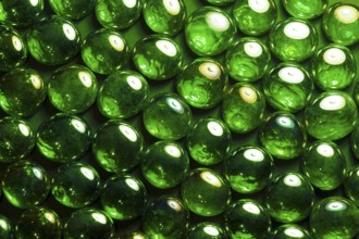 Full frame abstract background picture with iridescent green glass beads in dark back