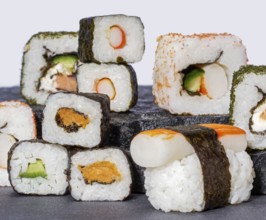 Various sushi dishes on dark grey stone surface