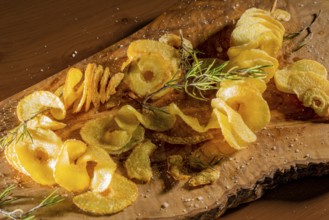 Some deep-fried spiral-sliced potatoes with some thyme on wooden board