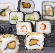Various sushi dishes on dark grey stone surface