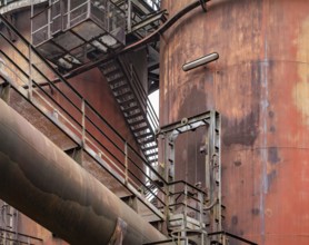 Weathered rundown industrial scenery with old corroded steel girders, stairs and metal tubes