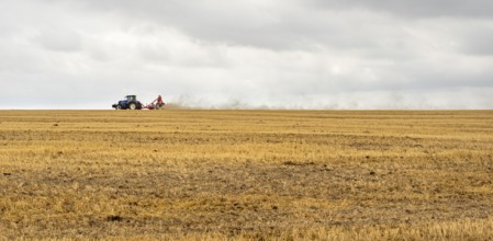 Stormy farmland scenery showing a Tractor on a stubble field in Hohenlohe, an area in Southern