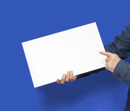 Male person holding a white blank sign in blue back