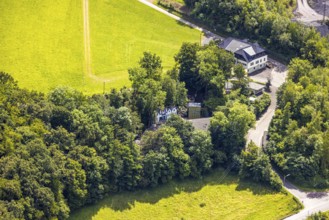 Aerial view, open-air stage covered by trees and adjacent buildings with towers, on the right