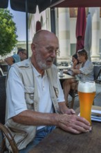 Elderly man with beard holding wheat beer glass, Dornbirn, Vorarlberg, Austria