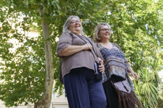 Two cheerful senior women enjoying a walk together in a park, celebrating their love, diversity,