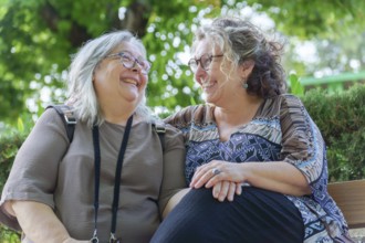 Two cheerful women enjoying each other's company on a park bench, representing lgbtq love,