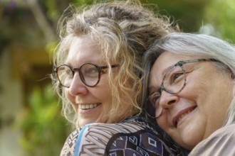 Two happy senior women are hugging each other outdoors, enjoying a moment of affection and