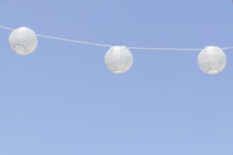 White paper lanterns decorating an outdoor space, adding a festive touch against a clear blue sky