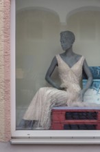 Shop window with grey fashion mannequin in evening dress, Bavaria, Germany