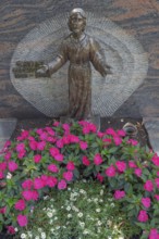Gravesite with Christ figure and floral decorations, noble lily (Impatiens New Guinea) Catholic