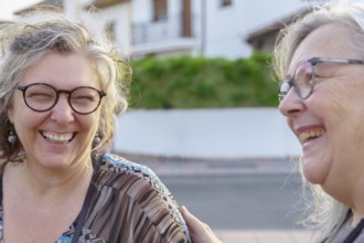 Two cheerful senior women enjoying each other's company outdoors, sharing laughter and happiness