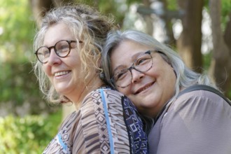 Happy mature lesbian couple enjoying a tender moment together in nature, celebrating their love and
