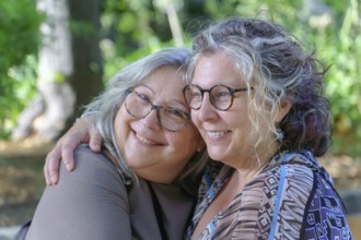 Two mature women embracing each other tenderly in a park, celebrating their love and connection
