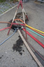 Water hoses and warning triangle on tarmac above open gully, Circus-Krone, Kempten, Allgäu,