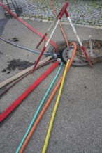 Water hoses and warning triangle on tarmac above open gully, Circus-Krone, Kempten, Allgäu,
