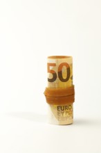 Close-up of fifty euro banknotes rolled up and secured with a rubber band, symbolizing savings,