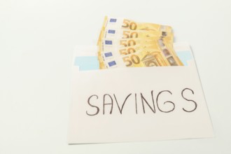 Euro banknotes in an envelope labeled savings illustrating the concept of personal finance and