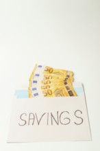 Envelope containing fifty euro banknotes and the word savings represents the concept of