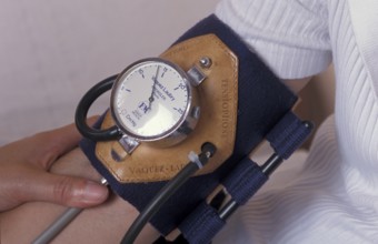 A close-up of a blood pressure monitor on a person's arm with a leather gauge attachment