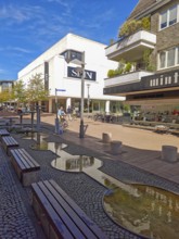 Pedestrian zone with fountain, department stores', pedestrians, traffic-calmed, young trees,