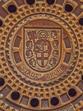 Round manhole cover with city coat of arms, Cologne collegiate cross, St Peter in cloak, key, book,