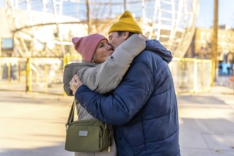 Elderly couple sharing a tender kiss and hug in a festive winter cityscape, celebrating love and
