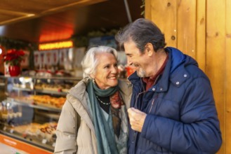Happy senior couple smiling and enjoying time together during christmas holidays at a winter market