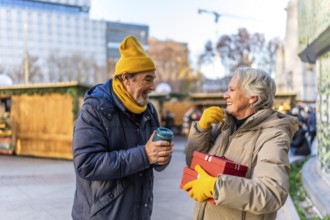 Elderly couple exchanging christmas presents and enjoying a hot beverage at a traditional christmas