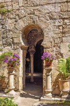 Flowers on pedestals at an opening into the Arab baths old building with oriental architecture,