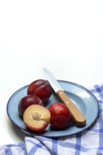 Red plums on plate with kitchen knife, Prunus domestica