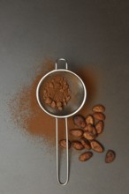Kitchen sieve with cocoa powder, cocoa and cocoa beans