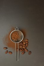 Kitchen sieve with cocoa powder, cocoa and cocoa beans